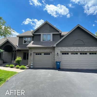 Townhouse in gray siding with stone detailing and twin garage doors