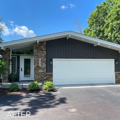 Single-story house in charcoal board and batten siding with a stone-faced entry