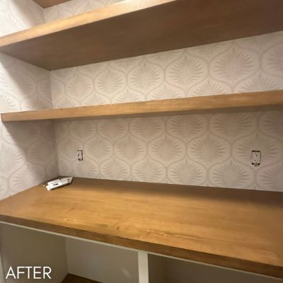 Office nook papered in a pale fan print behind floating oak shelves