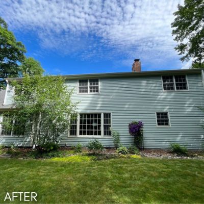 Rear elevation of a house in pale green siding with white window trim