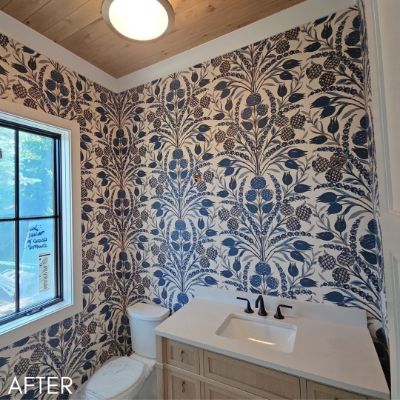Powder room papered in a blue and cream floral print below a wood ceiling