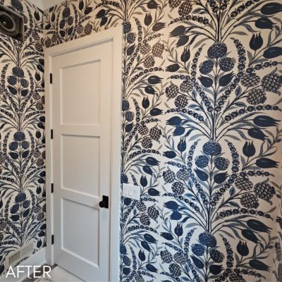 Powder room papered in a blue tulip print beside a white panelled door