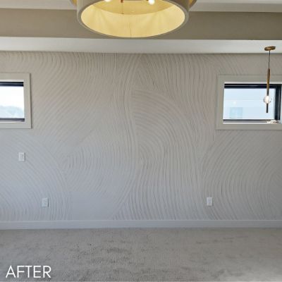 Room hung with a pale wave-patterned wallcovering between two windows