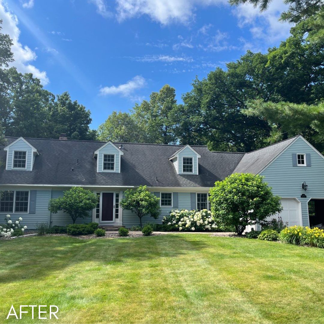 Cape Cod house in pale green with white dormers behind a mown lawn