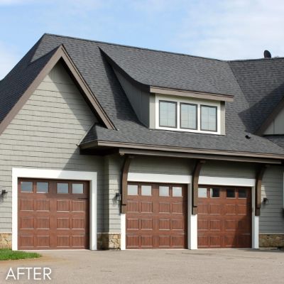 Gabled house in sage green siding with three wood garage doors