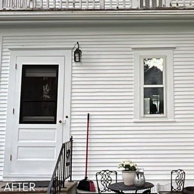 White clapboard wall and storm door above a small patio