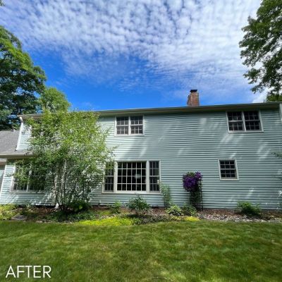Two-story house in pale sage siding with white window trim