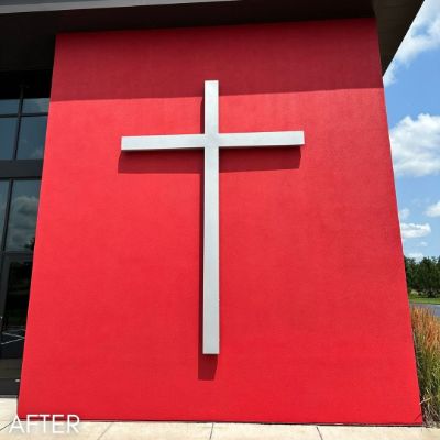 Church facade painted bright red behind a tall white cross
