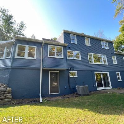 Three-story house in deep blue siding with white window trim