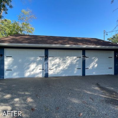 Detached garage with three white doors against navy siding