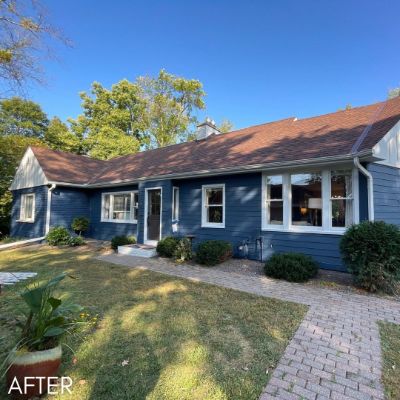 Single-story house in navy siding with white trim and a paved path