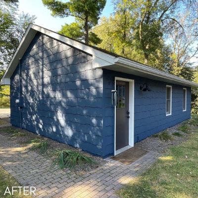Detached garage in slate blue siding with a gray service door