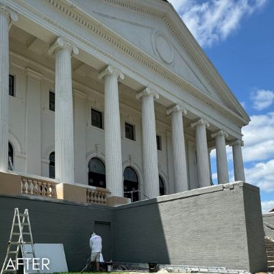 Church portico during painting, white columns above a freshly coated gray wall