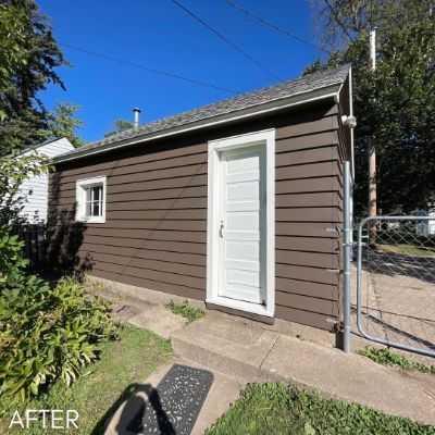 Garage in brown siding with a white service door