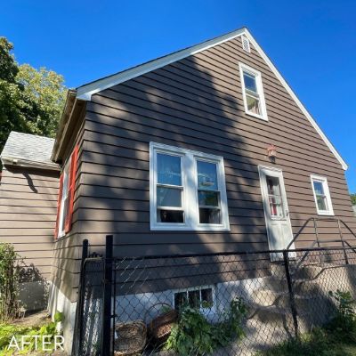 Gambrel-roofed house in brown siding with red window trim
