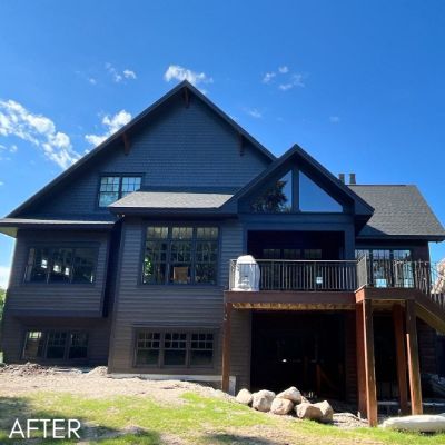 Large house in charcoal siding with stained timber posts and a deck