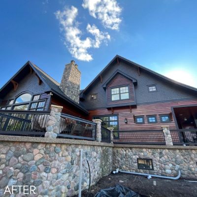 House in deep red and charcoal siding above a fieldstone retaining wall