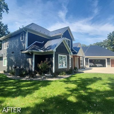 House in blue gray board and batten siding with a detached garage