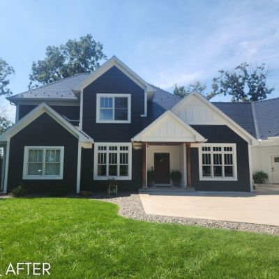 Single-story house in charcoal siding with cream gables and a timber porch