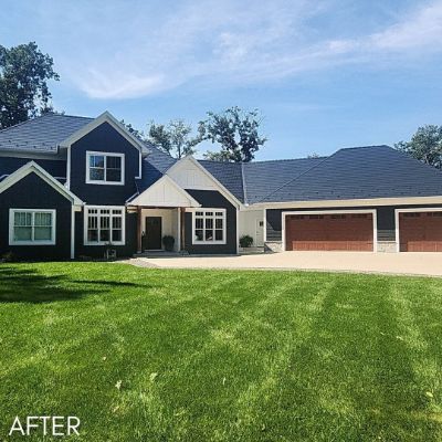 Long house in charcoal siding with cream trim and brown garage doors