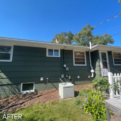 Side elevation of a house in dark green siding with white window trim