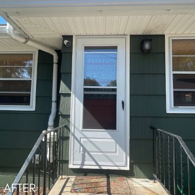 Entry and storm door in a dark green sided wall above a brick step