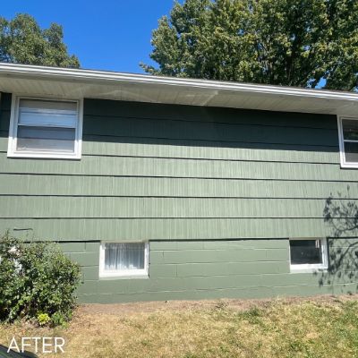 Rear elevation in dark green siding above a painted block foundation