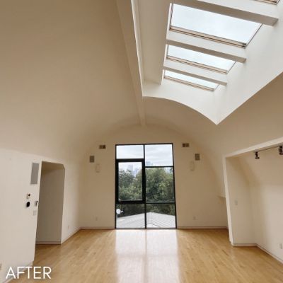 Vaulted room after painting, white walls below a run of skylights