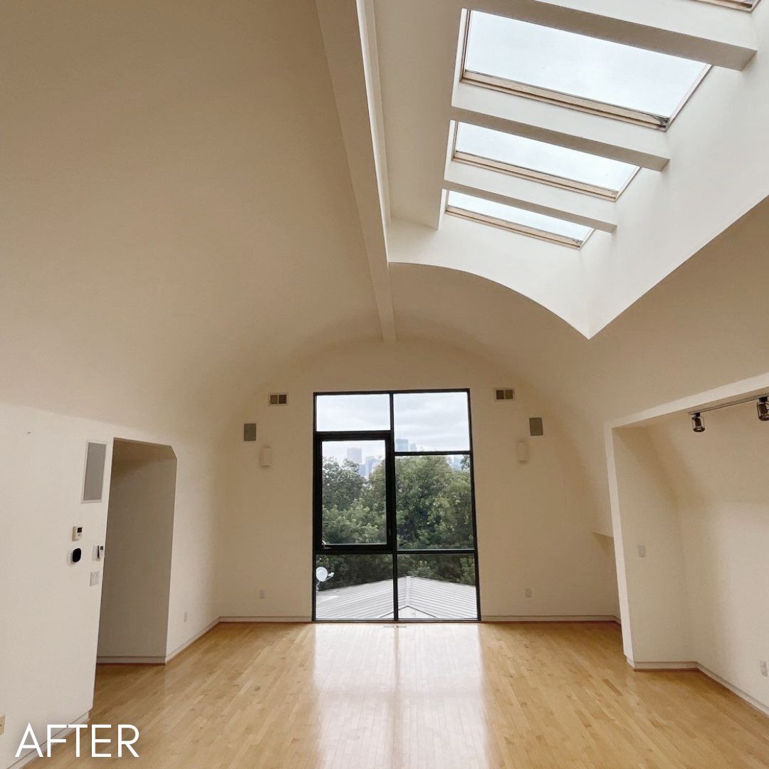 Vaulted room after painting, white walls below a run of skylights