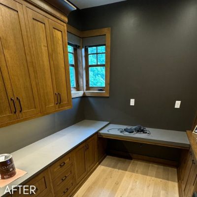 Home office with stained oak cabinetry against a dark olive wall