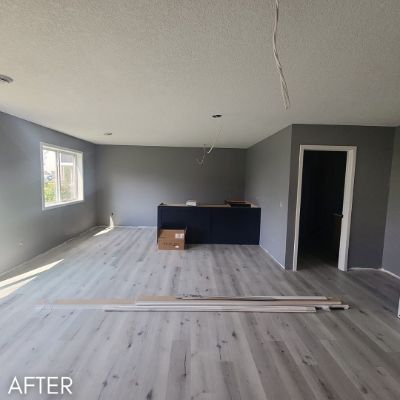 Empty room after painting, warm gray walls above pale wood flooring
