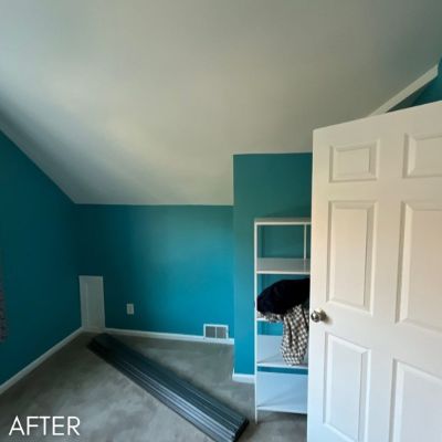 Attic bedroom after painting, with teal walls below a sloped white ceiling
