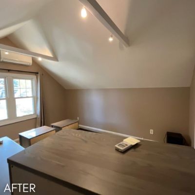 Attic room after painting, warm taupe walls below a vaulted white ceiling