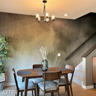 Dining area hung with a bronze ombre wallcovering below a brass chandelier