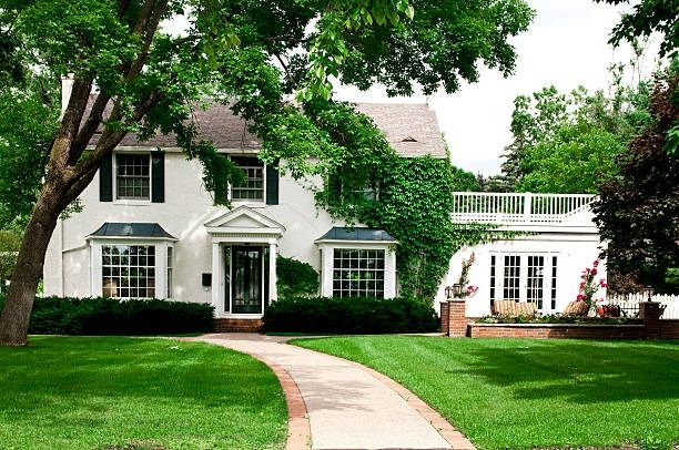 White painted brick colonial house with black shutters and an ivy-covered wing