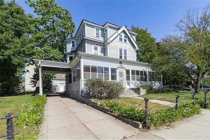 Three-story Victorian house in pale blue and white, with a wraparound porch