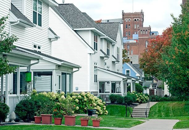 A row of white clapboard houses along a city street, with a brick tower behind them