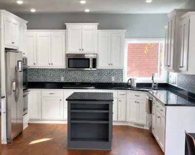 Kitchen with refinished white shaker cabinets, a gray island and black granite counters